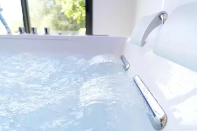 a bath tub filled with water next to a window at Romantic suite with jacuzzi in La Trinité