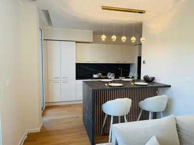 a kitchen with a bar with two white stools at LE PALAIS DIANE - Apt cosy, Moderne et Climatisé in Nice