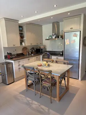 a kitchen with a table and chairs and a refrigerator at Appartement 2 chambres, terrasses, proche mer et commerces à Saint-Jean Cap Ferrat in Saint-Jean-Cap-Ferrat