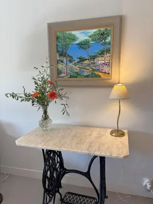 a table with a vase of flowers and a painting at Appartement 2 chambres, terrasses, proche mer et commerces à Saint-Jean Cap Ferrat in Saint-Jean-Cap-Ferrat
