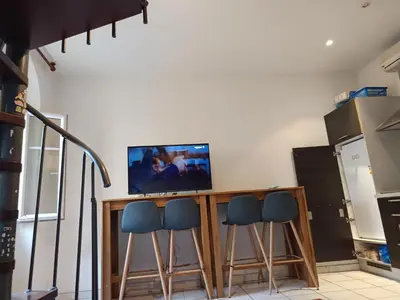 a kitchen with a bar with four stools and a television at Studio in Nice