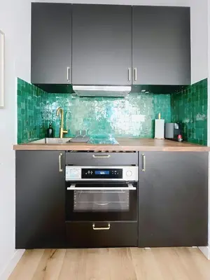 a kitchen with black appliances and green tiles at Sunny studio on a high floor with terrace in Nice