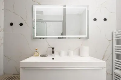 a white bathroom with a sink and a mirror at Bord de mer - Beau 2 pièces rénové - Parking - EX in Èze