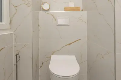 a white toilet in a bathroom with marble walls at Bord de mer - Beau 2 pièces rénové - Parking - EX in Èze