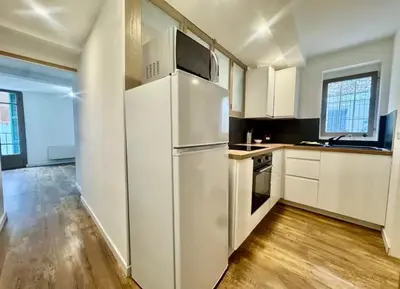 a kitchen with white cabinets and a refrigerator at Superbe deux pièces dans le vieux village in Saint-Laurent-du-Var