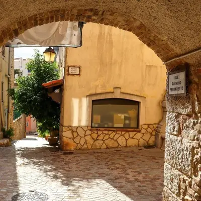 a stone building with an archway on a street at Superbe deux pièces dans le vieux village in Saint-Laurent-du-Var