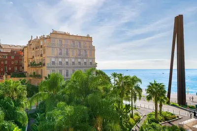 a building next to the ocean with palm trees at 