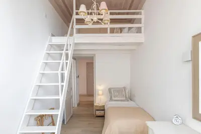 a room with white bunk beds and a ladder at 