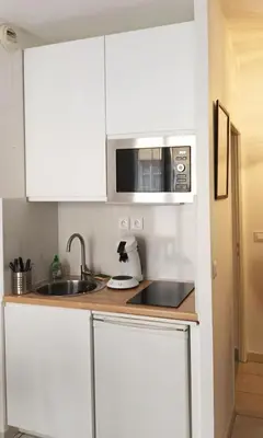 a kitchen with white cabinets and a sink and a microwave at Plein centre, calme et cosy in Nice
