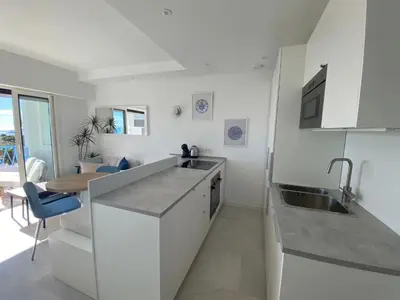 a white kitchen with a sink and a table at mure in Beaulieu-sur-Mer