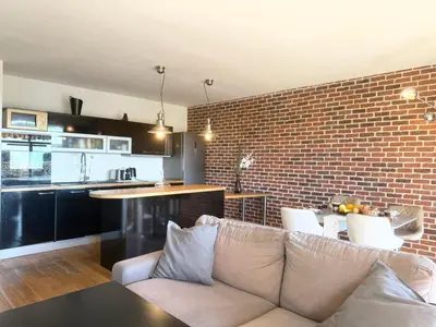 a living room with a couch and a brick wall at 2 pièces cosy avec grande terrasse & piscine in Cagnes-sur-Mer
