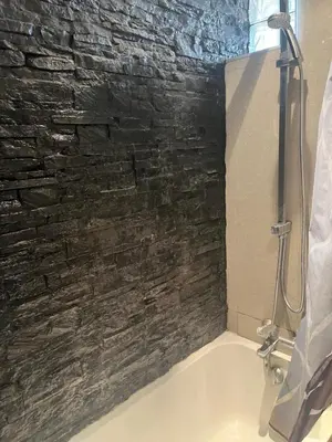 a bathroom with a stone wall and a bath tub at 2 pièces cosy avec grande terrasse & piscine in Cagnes-sur-Mer
