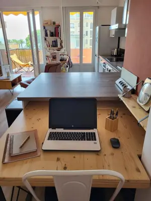 a laptop computer sitting on a wooden table in a kitchen at 2P cosy avec terrasse, vue mer & plages à pied in Nice