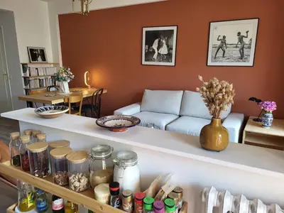 a living room with a couch and a shelf with jars at 2P cosy avec terrasse, vue mer & plages à pied in Nice