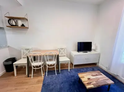 a living room with a table and chairs and a tv at Beaumont Résidence in Nice