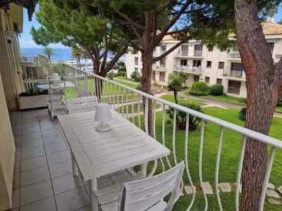 a balcony with a white table and chairs and a building at Centre ville de St Jean Cap Ferrat in Saint-Jean-Cap-Ferrat