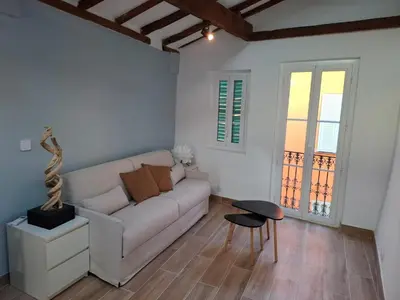 a living room with a white couch and a table at Charmant studio rénové – Place de la République in Villefranche-sur-Mer