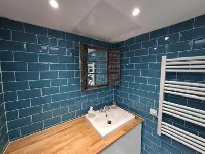 a blue tiled bathroom with a sink and a mirror at Charmant studio rénové – Place de la République in Villefranche-sur-Mer