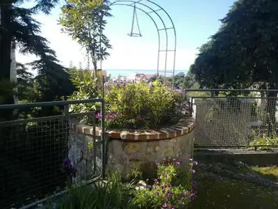 a garden with flowers and a fence and a swing at 1 chambre chez l'habitant, vue mer, ville et plage in Nice