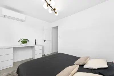 a white bedroom with a black bed and white cabinets at Spacieux 4 pièces - Balcon - Parking - FC in Saint-Laurent-du-Var