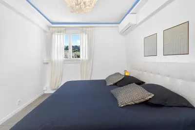 a bedroom with a bed with blue sheets and a window at Spacieux 4 pièces - Balcon - Parking - FC in Saint-Laurent-du-Var