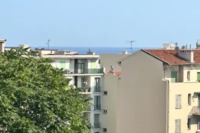 a white apartment building with a tree in the foreground at Studio with veranda 5min walk to the beach in Nice
