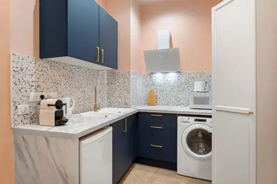 a kitchen with blue cabinets and a washer and dryer at Cocon stylé Centre et mer à pied CLIM WIFI in Nice