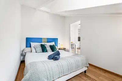 a white bedroom with a large bed with a blue headboard at Charmant 2p au port de Nice - Calme et climatisé in Nice