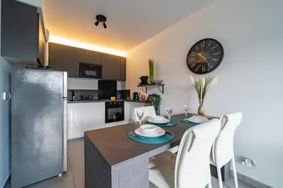 a kitchen with a dining table and a clock on the wall at Superbe 2 pièces - Piscine et garage in Nice