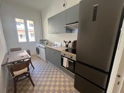 a kitchen with a refrigerator and a sink and a table at 2P de charme proche gare et hyper centre Nice in Nice
