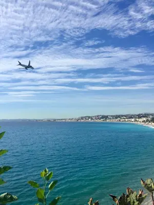 a plane flying over the water with a beach at Atelier de Lumière Nice Gambetta in Nice