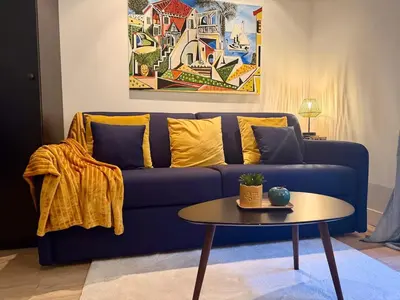 a blue couch with yellow pillows and a table at Studio design et lumineux près du Port de Nice in Nice