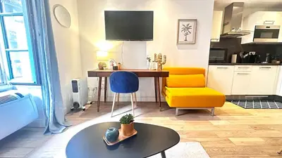 a living room with a table and a yellow chair at Studio design et lumineux près du Port de Nice in Nice