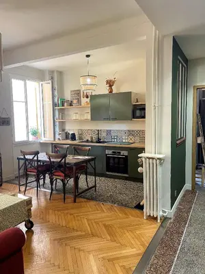 a living room with a table and a kitchen at Appartement 2 pièces bourgeois meublé, aéroport tramway in Nice