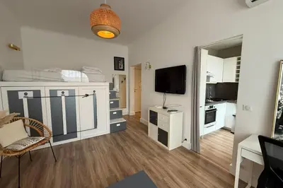 a living room with a television and a white room at Beautiful studio apartment just a stone's throw from the beach in Nice