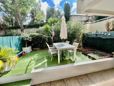 a small backyard with a table and chairs on grass at Le riviera bay avec parking in Saint-Laurent-du-Var