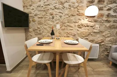 a wooden table with chairs and a bottle of wine at Studio de charme - Vieille Ville - Proche plage in Villefranche-sur-Mer