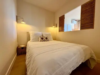 a bedroom with a large white bed with a window at Studio cosy - Vue mer - Terrasse - Parking in Saint-Laurent-du-Var