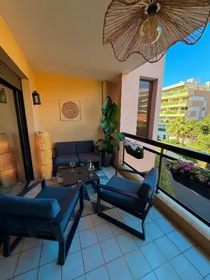 a living room with a couch and chairs on a balcony at Appartement moderne climatisé avec piscine, terrasse et parking - Proche Promenade des Anglais in Nice