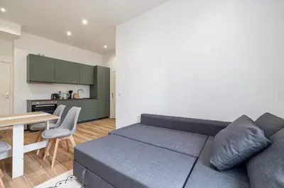a living room with a couch and a table and a kitchen at Au cœur de Nice, Gare à pied et Climatisation in Nice
