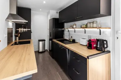 a kitchen with black cabinets and a wooden counter top at Le Pin - Peaceful - Parking - Comfort - AC in Saint-Laurent-du-Var