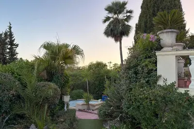 a garden with palm trees and a building with a pool at Studio indépendant en villa Calme, Jardins et Piscine à 5 min de la Mer in Nice