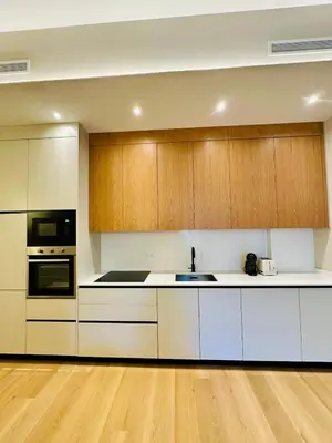 a kitchen with white counters and wooden cabinets at Appartement neuf d architecte Carré d Or in Nice