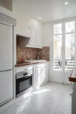 a kitchen with white cabinets and a sink and a window at Blanche - From Nice with love in Nice