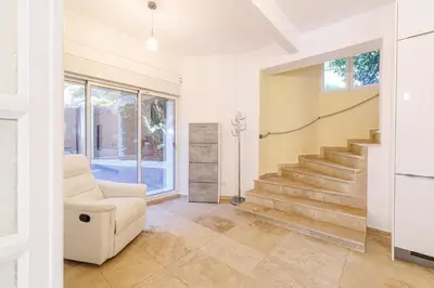 a living room with a white chair and stairs at VILLA MARIE -Pool - Garden-Close To Beach -Parking in Nice