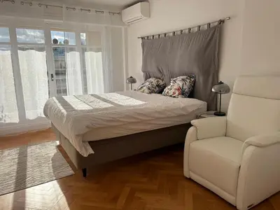 a bedroom with a bed and a white chair at Appartement T3 NICE Promenade des Anglais in Nice