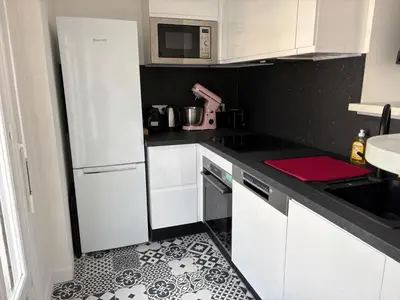 a kitchen with white cabinets and a black and white floor at Appartement T3 NICE Promenade des Anglais in Nice