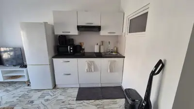 a small kitchen with white cabinets and a refrigerator at Cosy 1 Bedroom, balcony, Promenade des Anglais in Nice