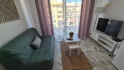 a living room with a green couch and a television at Cosy 1 Bedroom, balcony, Promenade des Anglais in Nice