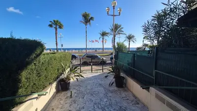 a patio with a fence and palm trees and a car at Cosy 1 Bedroom, balcony, Promenade des Anglais in Nice